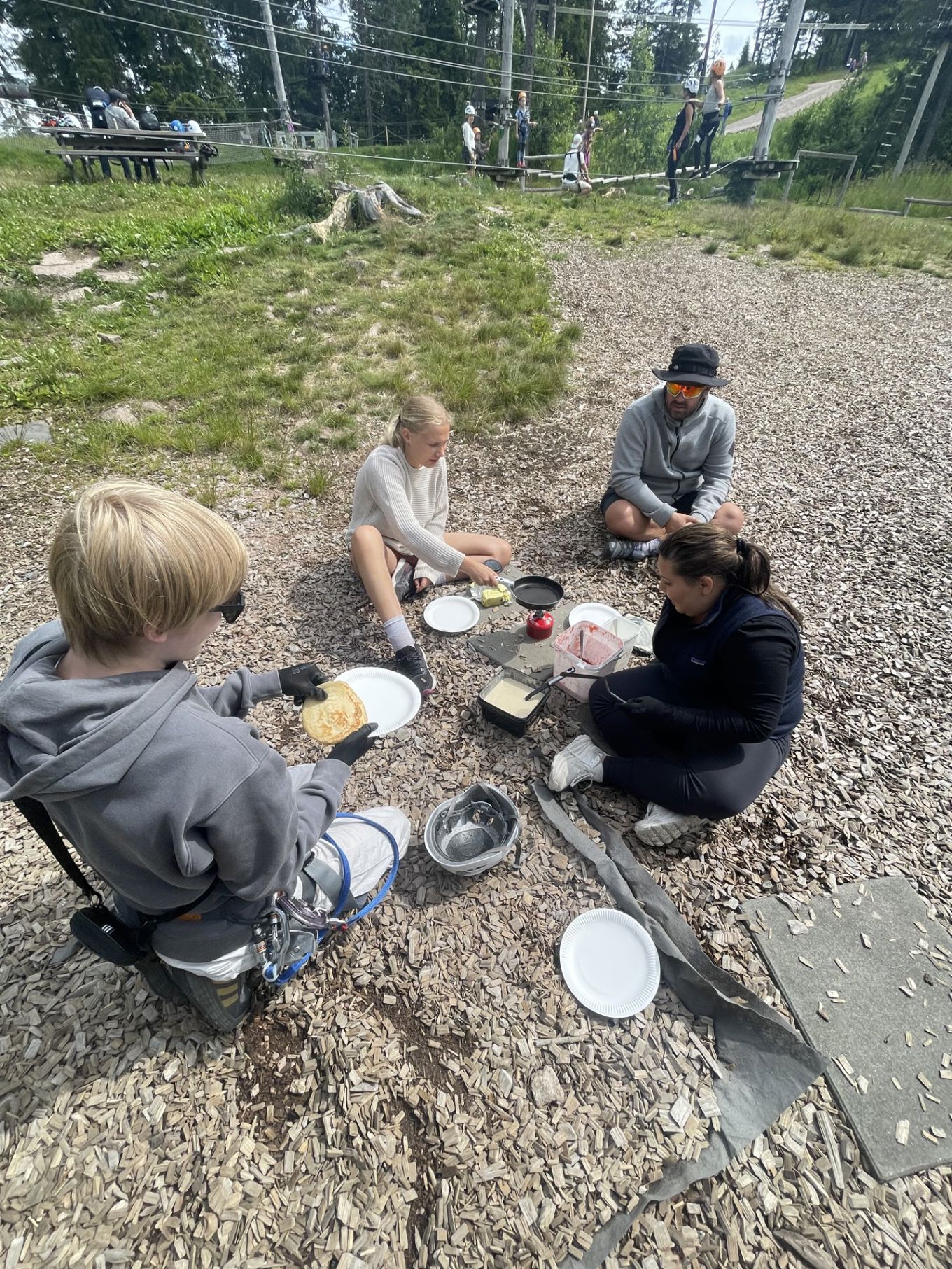 en gruppe mennesker som sitter på en stein med mat og drikke